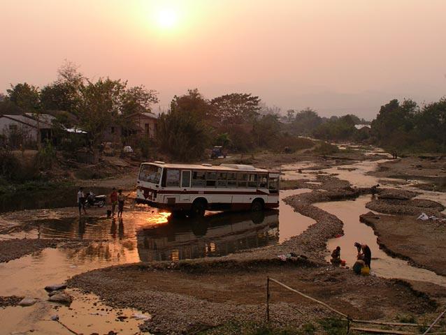 Laundry and a bus being wahsed side by side in the river in Hsipaw.